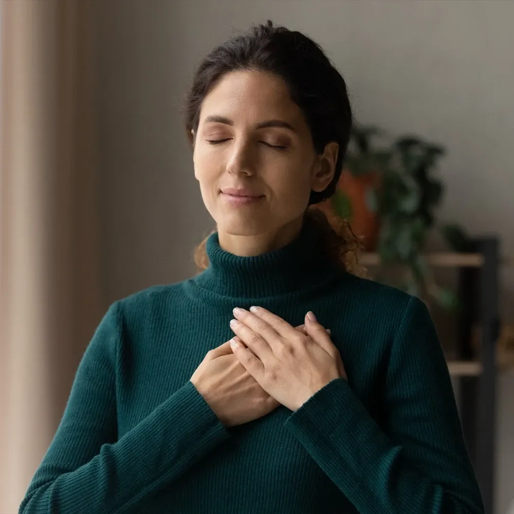 A woman with eyes closed and hands on her chest